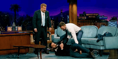 two men are fighting on a couch with a roosevelt hotel sign in the background