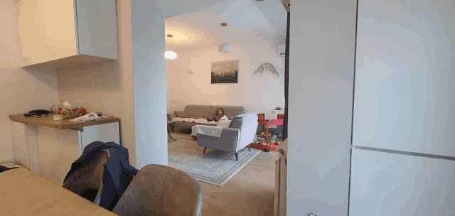 a girl sits on a couch in a living room with a painting on the wall