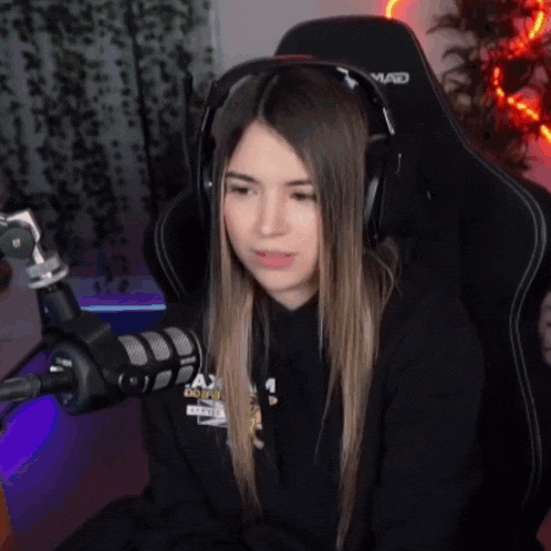 a girl wearing headphones is sitting in front of a microphone and a chair that says mad