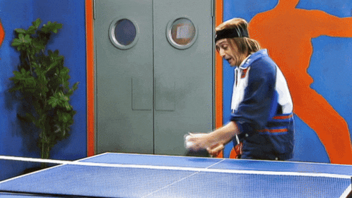 a man wearing a headband playing ping pong on a table