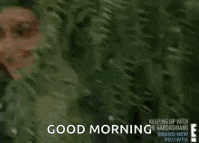 a woman is smiling while standing next to a tree and says `` good morning '' .