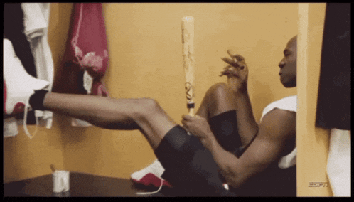 a man is holding a baseball bat in a locker room
