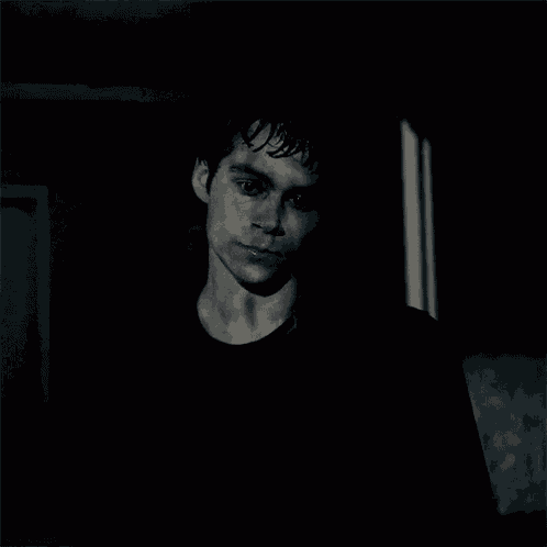 a black and white photo of a young man in a dark room