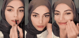 a woman wearing a hijab is applying lip gloss to her lips