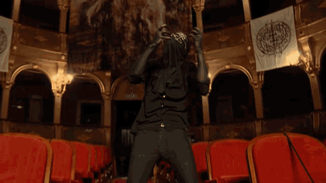 a man in a black mask is singing into a microphone