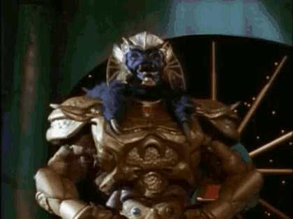 a statue of a warrior with a blue face and gold armor is standing in front of a dart board .