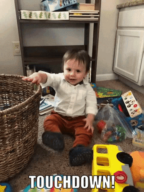 a baby is sitting on the floor with a basket full of toys and the words touchdown on the bottom