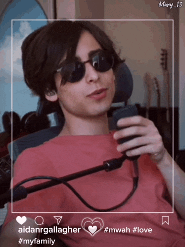 a young man wearing sunglasses and a pink shirt is holding a microphone in his hand