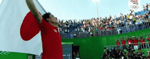 a man in a red shirt is holding a japanese flag in front of a crowd of people sponsored by claro sports