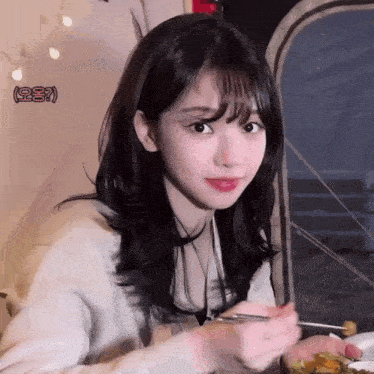 a girl eating a meal with chopsticks and a sign that says ' korean ' in the corner
