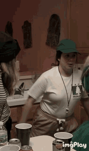 a woman wearing a shirt that says wald is standing in a kitchen