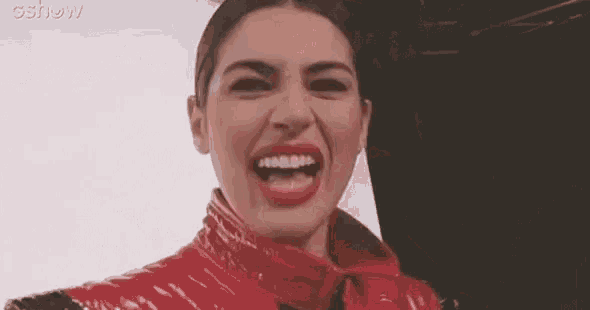 a woman wearing a red jacket is making a funny face .