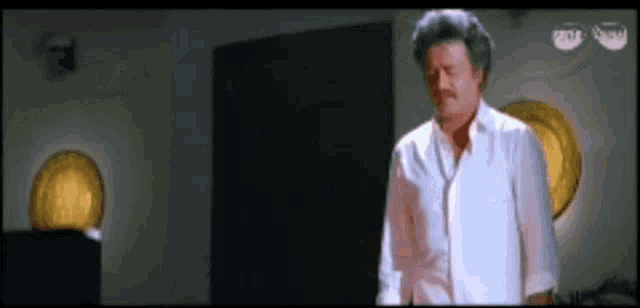 a man in a white shirt is standing in a dark room with a sign that says visa