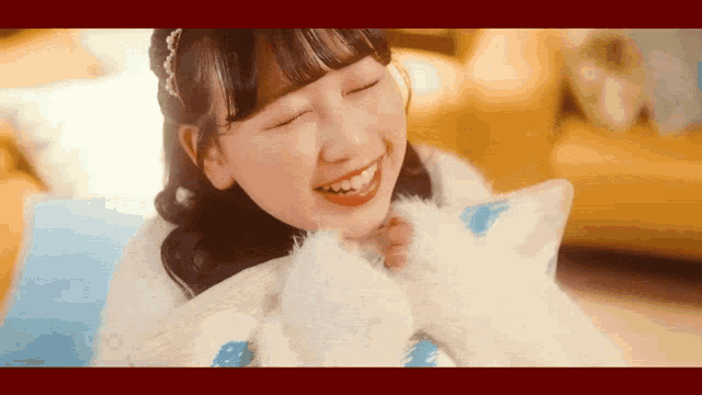 a girl is smiling while holding a white stuffed animal