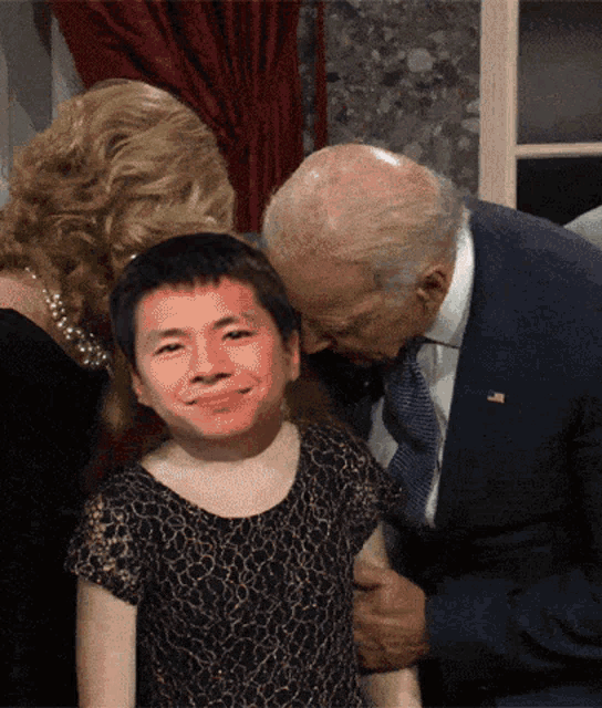 a man in a suit and tie is kissing a little girl on the cheek