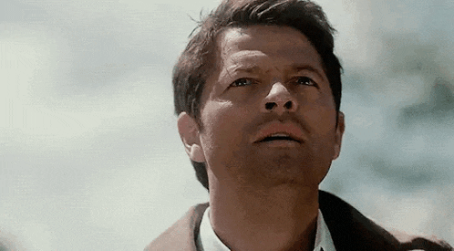 a man is looking up at the sky while wearing a suit and tie .