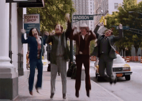 a group of people jumping in the air in front of a coffee shop