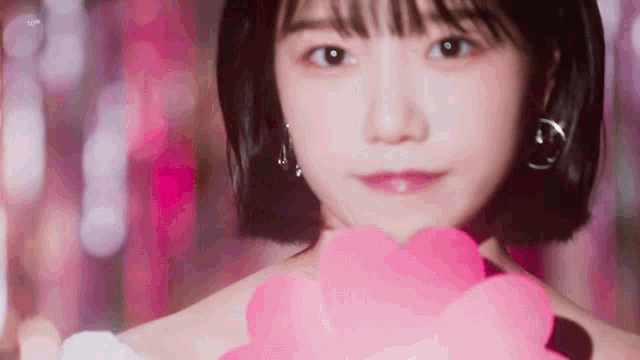 a close up of a woman holding a pink flower in her hand .