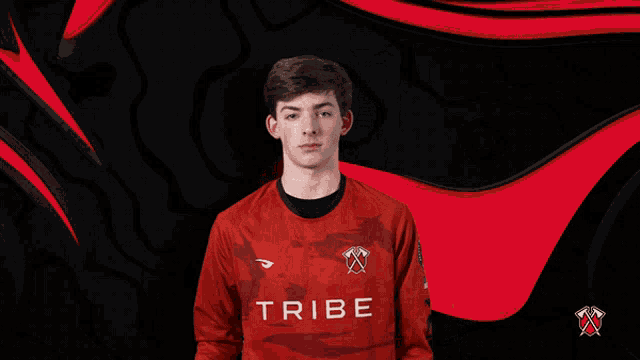 a man wearing a red tribe jersey stands with his hands folded