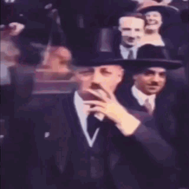 a man in a suit and top hat smoking a cigarette
