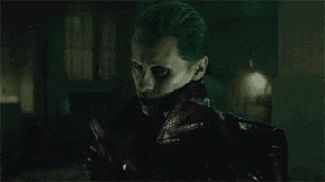 the joker from the movie suicide squad is looking at the camera with a serious look on his face .