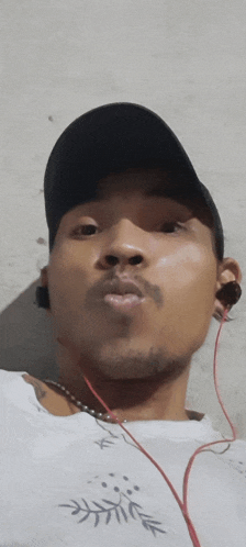 a man wearing a black hat and ear buds looks at the camera