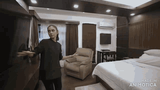 a woman stands in a bedroom with the words made in animotica on the bottom right