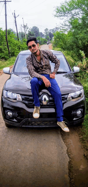a man sits on the hood of a black car
