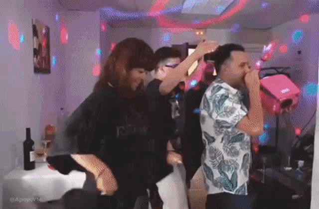 a group of people are dancing in a room with a bottle of wine in the foreground