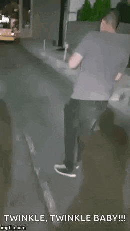 a man is riding a skateboard down a street while another man looks on .