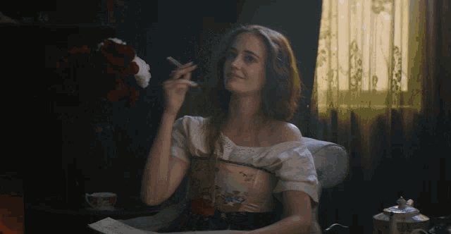 a woman is smoking a cigarette while sitting at a table