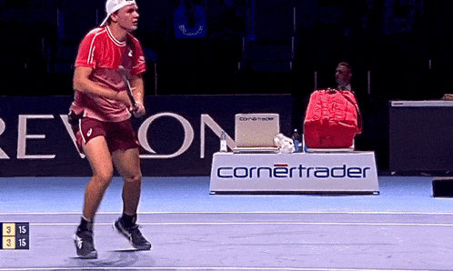 a man is playing tennis on a court with a cornertrader sign in the background
