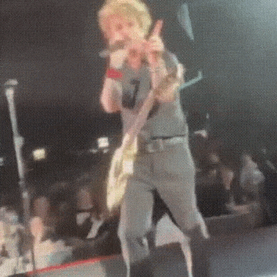 a man is playing a guitar and singing into a microphone while standing on a stage .