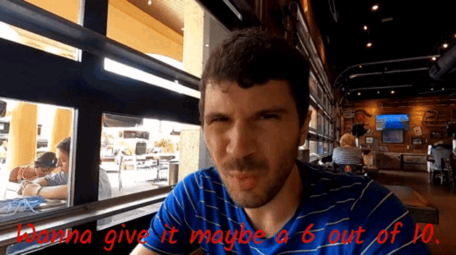a man sitting in a restaurant with the words wanna give it maybe 6 out of 10