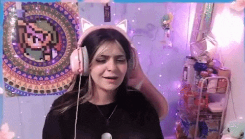 a woman wearing headphones with cat ears is sitting in front of a purple wall with a pixel art on it .