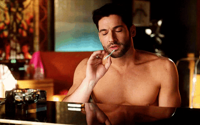 a shirtless man smoking a cigarette with a lighter in his mouth