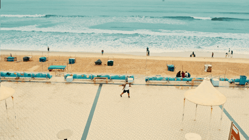 a man is playing tennis on a beach with a sign that says no diving