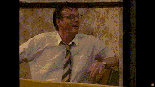 a man in a white shirt and tie is looking out a window .