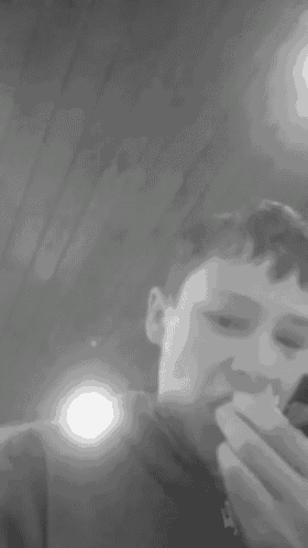 a black and white photo of a boy eating a sandwich