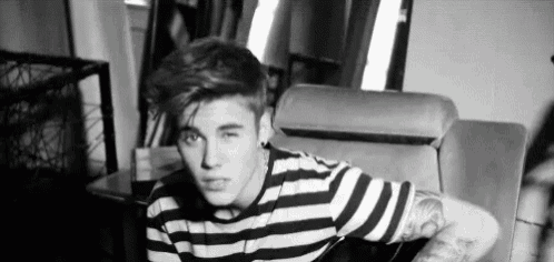 a black and white photo of a young man wearing a striped shirt .