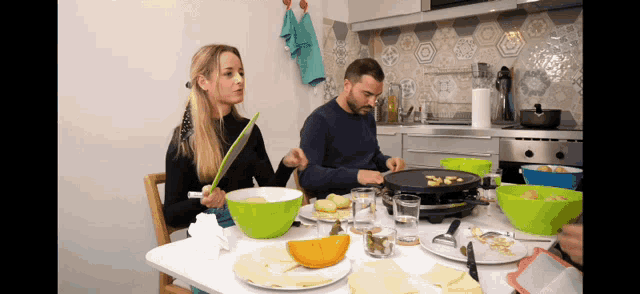 a man and a woman are sitting at a table with bowls of food