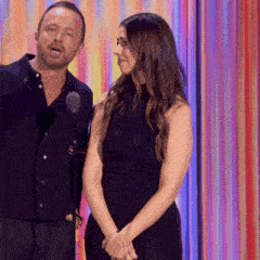 a man and a woman stand in front of a microphone