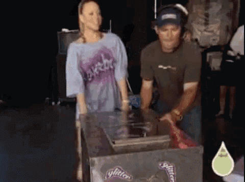 a man and a woman are standing in front of a box that says glitter on it