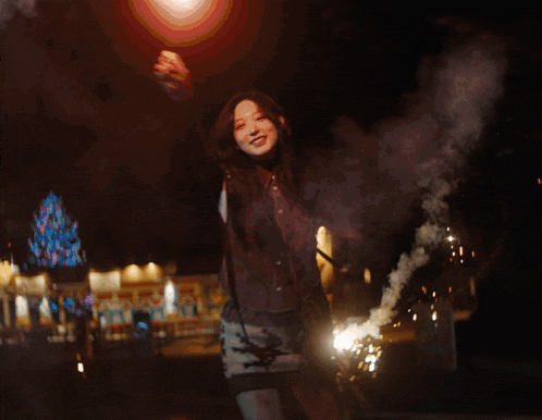 a blurry picture of a person holding a firework display with a christmas tree in the background