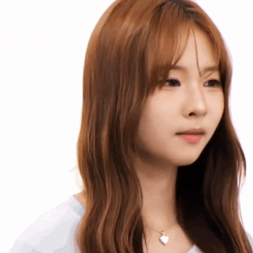 a woman with long brown hair is wearing a white shirt and a heart necklace .