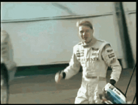 a man in a racing suit is dancing in front of a building .