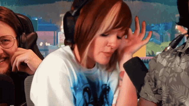 a woman wearing headphones is sitting in front of a man with glasses