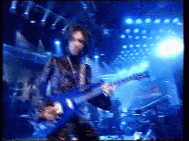 a blurry image of a man playing a guitar on stage