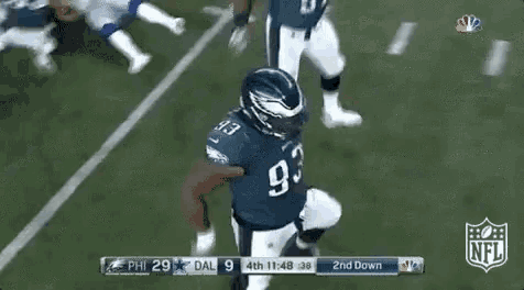 two eagles football players are running on the field during a game .