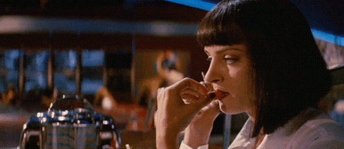 a woman in a white shirt is eating a strawberry